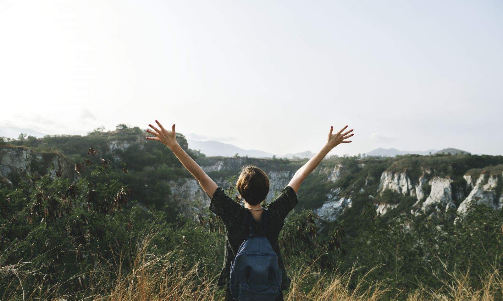 person outside with arms outstretched enjoying nature